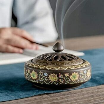 Човек държи Бутиков тамянник Флоранс 3в1 на маса.