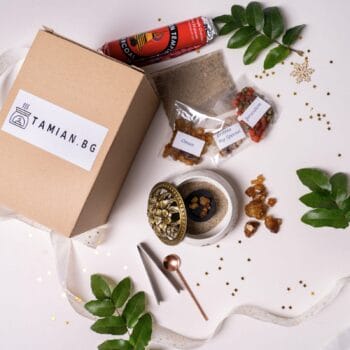 "Комплект Планински пейзаж" от Tamian.bg, включващ картонена кутия, метална поставка за тамян, щипки, пакетчета смола, малко бурканче и декоративни листа върху бяла повърхност.