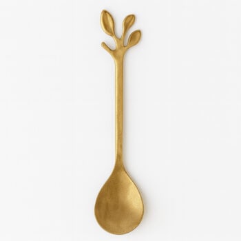 Златиста лъжичка за тамян има златисто покритие и дръжка с форма на три листа или клонки, заснети на обикновен бял фон.